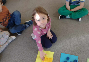 Dzieci przyporządkowują klocki do kolorowych kartek, a później rozwiązują zagadki matematyczne