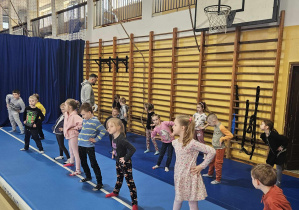 Grupa dzieci ćwiczy na sali gimnastyczne