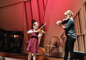 Dziewczynka z nauczycielka grają na skrzypcach.