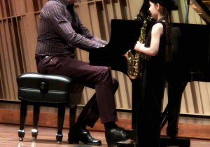 Dziewczynka z akompaniatorem gra na saksofonie