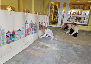 Dzieci rysują na tarasie kamienice z ulicy Piotrkowskiej.