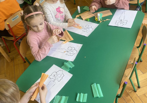 Dzieci siedzą przy stolikach, wykonują pracę plastyczną - marchewkę