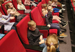 Dzieci siedzą na widowni i oglądają spektakl