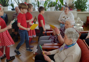 Dzieci wręczają kartki wielkanocne seniorom.