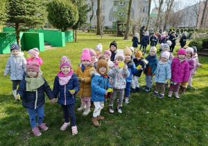 Dzieci stoją w ogrodzie, w ręku trzymają motylki