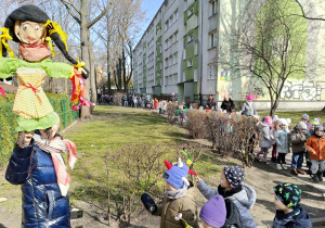 Dzieci maszerują po okolicy przedszkola, Pani trzyma w ręku Marzannę