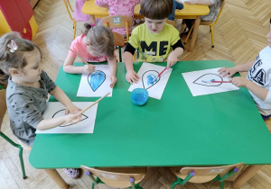 Dzieci siedzą przy stoliku, malują farbami kroplę wody