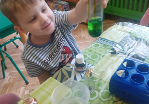 chłopiec pokazuje pojemnik z zabarwioną wodą