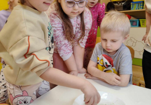 dzieci obserwują co dzieje się z mielonym pieprzem na powierzchni wody