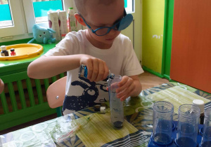 Chłopiec nalewa zabarwioną wodę do probówki