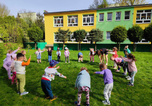 Dzieci wraz z trenerem stoją w kole, wykonują rozgrzewkę przed treningiem karate