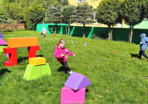 Dzieci pokonują tor przeszkód ułożony z różnych przyrządów sportowych i klocków wielkoformatowych