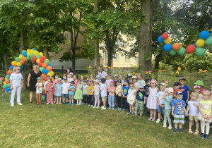 dzieci stoją w ogrodzie, śpiewają piosenki dla mamy i taty