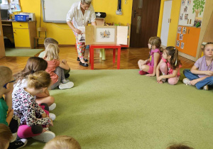 Pani pokazuje dzieciom planszę w teatrzyku kamischibai.