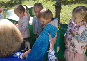 Pani trzyma dużą pluszową kredkę i pasuje dzieci na przedszkolaków