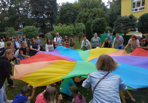 Dzieci i i rodzice biorą udział we wspólnych zabawach z chustą animacyjną