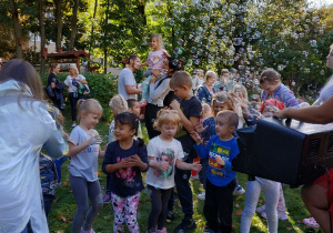 Dzieci i rodzice biorą udział w pokazie puszczania baniek mydlanych