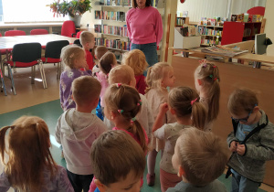 dzieci chodzą po bibliotece, słuchają Pani, która ich oprowadza