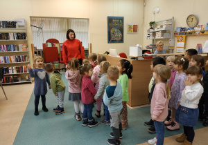 Dzieci są oprowadzane przez panią bibliotekarkę po bibliotece