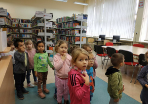 Dzieci są oprowadzane przez panią bibliotekarkę po bibliotece