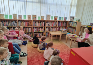 dzieci słuchają książki czytanej przez panią bibliotekarkę