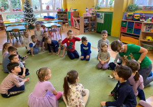 Dzieci siedzą na dywanie słuchając Pani Marty.