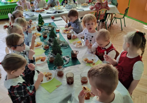 Dzieci siedzą przy stole, spożywają posiłek