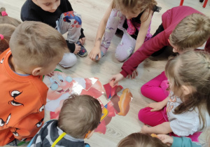 dzieci rozwiązują zadania: układają puzzle, rysują krasnoludka oraz wykonują zadanie matematyczne