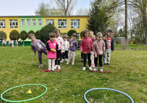 Dzieci biorą udział w konkurencjach sportowych w ogrodzie przedszkolnym.