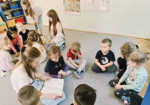 dzieci podzielone na dwie grupy siedzą na dywanie i wykonują zadania