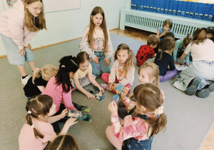 dzieci podzielone na dwie grupy siedzą na dywanie i wykonują zadania