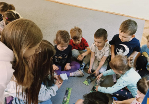 dzieci podzielone na dwie grupy siedzą na dywanie i wykonują zadania