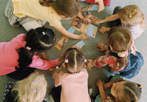 dzieci podzielone na dwie grupy siedzą na dywanie i wykonują zadania