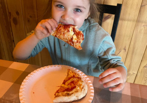 dziewczynka je przygotowaną przez siebie pizzę