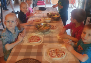 Dzieci przygotowują swoje pizze do wypieku