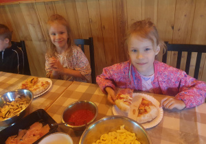 Dziewczynki jedzą przygotowane przez siebie pizze
