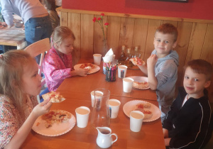 Dzieci jedzą przygotowane przez siebie pizzę