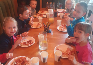 Dzieci jedzą przygotowane przez siebie pizzę