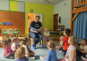 Dzieci siedzą i słuchają bajki czytanej przez rodzica