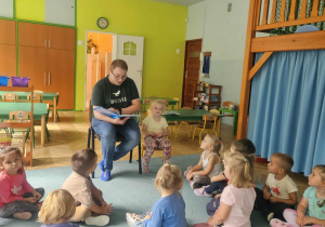 Dzieci siedzą i słuchają bajki czytanej przez rodzica