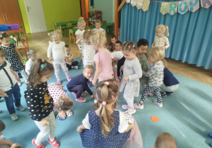 Dzieci biorą udział w zabawie ruchowej, omijając kolorowe kropki