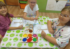 dzieci malują liście na drzewie farbami i pałeczkami do uszu