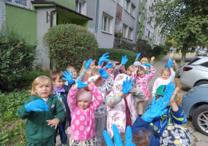 Dzieci stojące przy bloku z założonymi rękawiczkami rozpoczynające akcje sprzątanie Świata