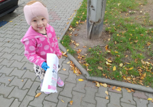 Dziewczynka podnosi śmieci z trawnika