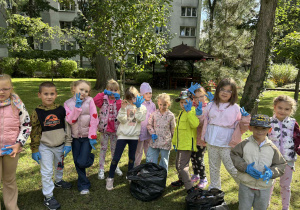dzieci pozują do grupowego zdjęcia wraz z workiem na śmieci