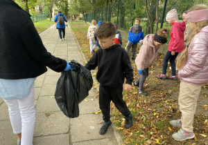 chłopiec wrzuca śmieci do worka