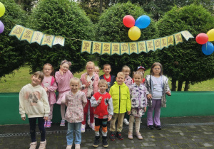 Dzieci stoją na tarasie przedszkolnym, pozują do zdjęcia grupowego