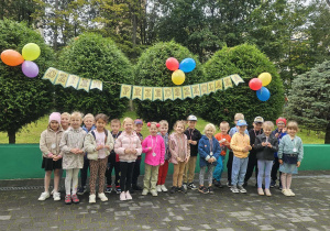 Dzieci stoją na tarasie przedszkolnym, pozują do zdjęcia grupowego