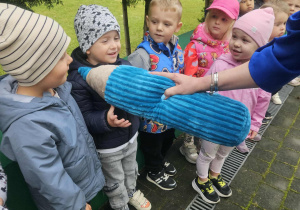 dzieci stoją na tarasie przedszkolnym, pani Dyrektor trzyma pluszową kredkę pasując dzieci na przedszkolaków
