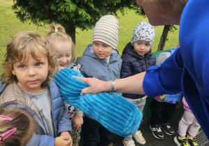 dzieci stoją na tarasie przedszkolnym, pani Dyrektor trzyma pluszową kredkę pasując dzieci na przedszkolaków